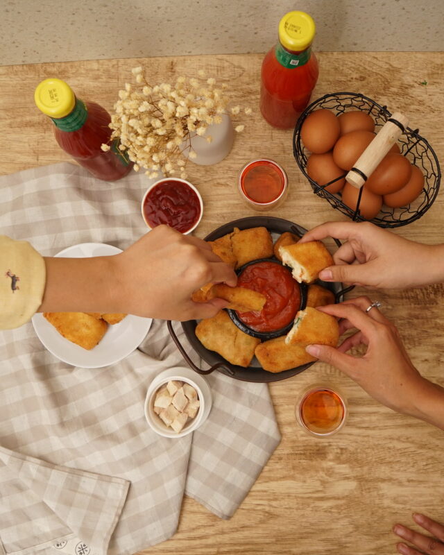 Beberapa tangan mengambil risoles dari satu piring di meja kayu